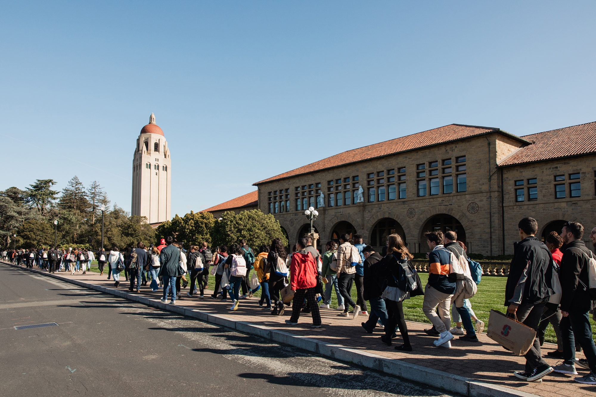 University Innovation Fellows walking across the Stanford campus with Hoover Tower in the background